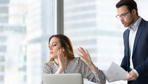 A man and woman, both in business attire, converse with each other 