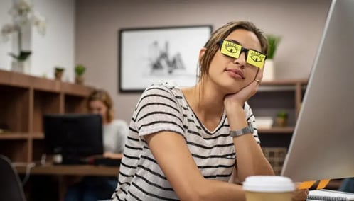 A woman with glasses is seated at a desk