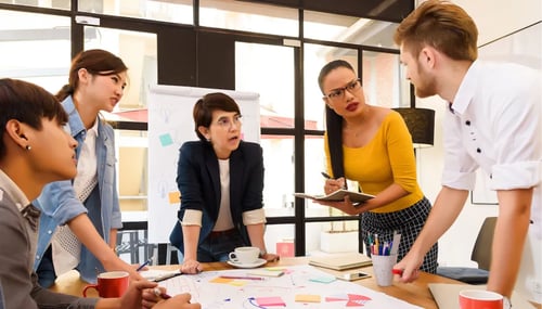 People gathered around a table with a whiteboard in a meeting room. 