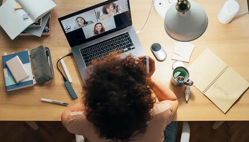 A woman at a desk, engaged with a laptop and a phone, focused on her tasks