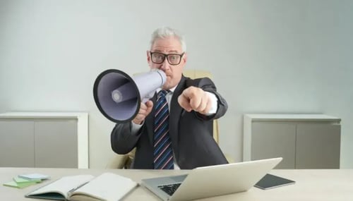 An older man in a suit and tie holds a megaphone