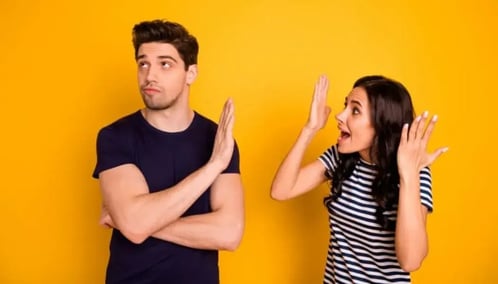 A man and woman stand together against a vibrant yellow background