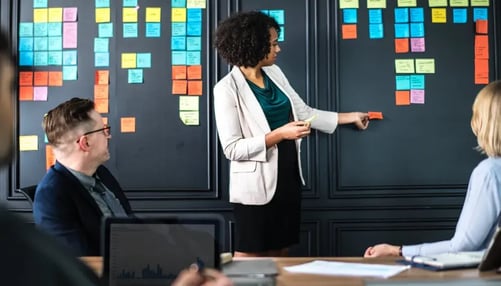 A woman sticking notes on board in a meeting