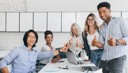 young professionals smiling and giving thumbs up