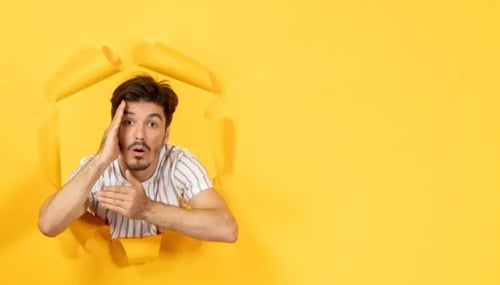 A man peers through a hole in a wall