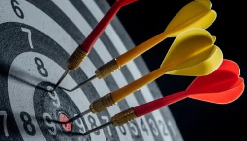 Darts striking the bullseye on a dartboard