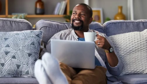 A man sitting on a sofa thinking something with a cup in his hand