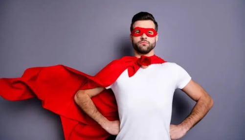 A man wearing a red cape and mask stands confidently